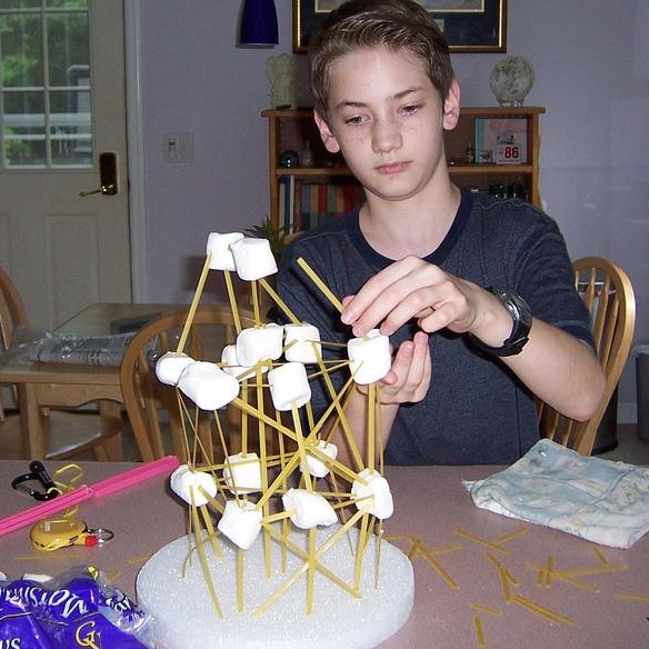 Un élève construit une structure avec des pâtes et des guimauves