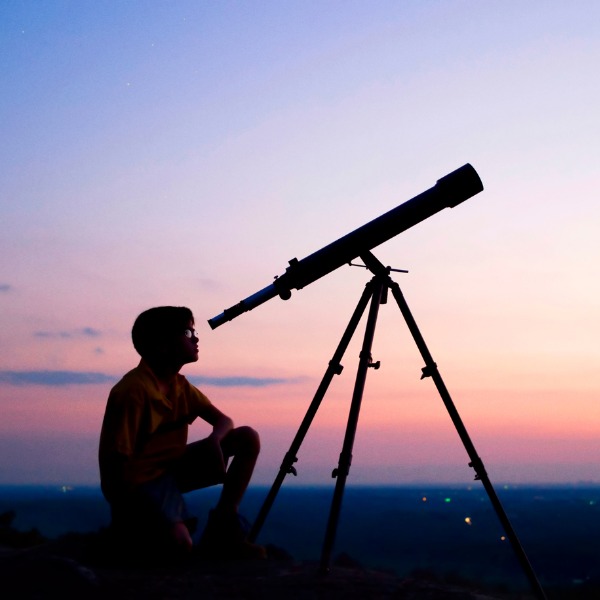 Garçon regardant le ciel nocturne dans un télescope