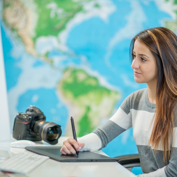 Femme travaillant à l'ordinateur devant une carte géographique