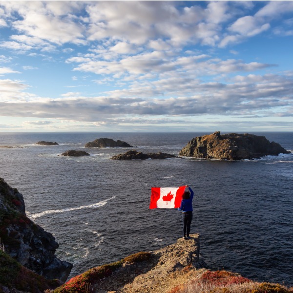 Femme avec un drapeau canadien près de l'océan