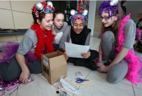 Quatre élèves sourient en lisant les instructions pour le volet défi de génie du Défi Parlons sciences.
