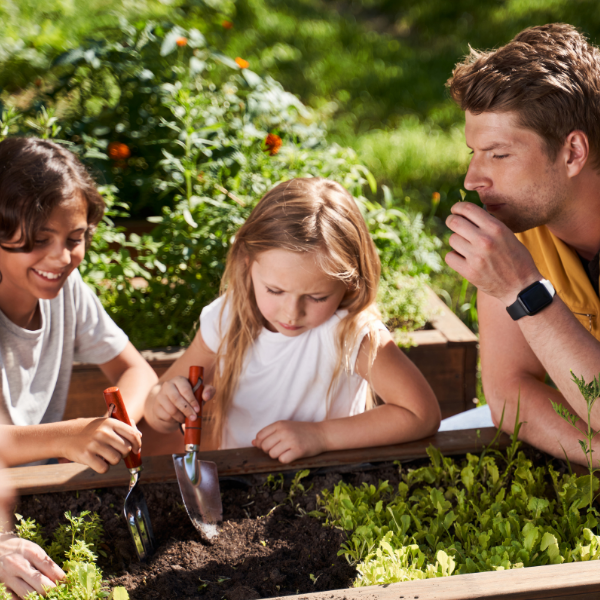 Enfants avec de petites pelles creusant dans le jardin avec un adulte