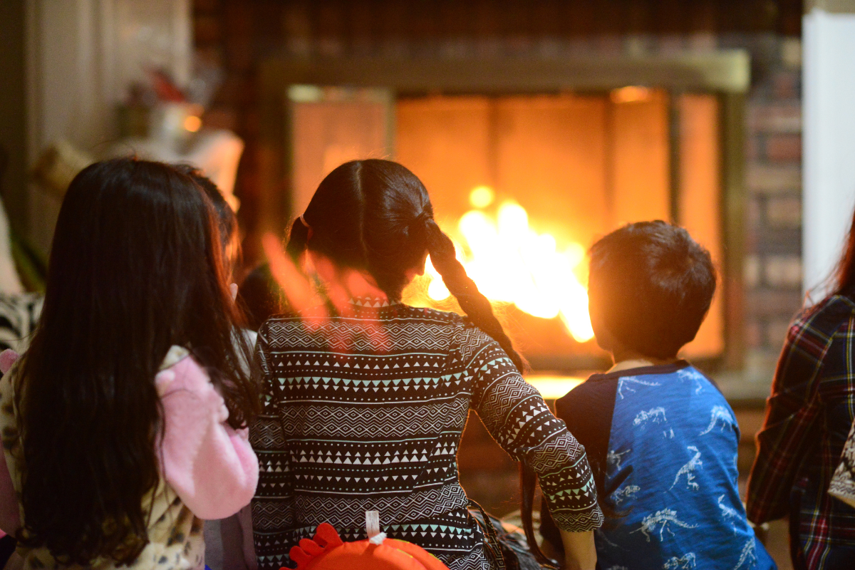 Des enfants assis devant un feu de foyer
