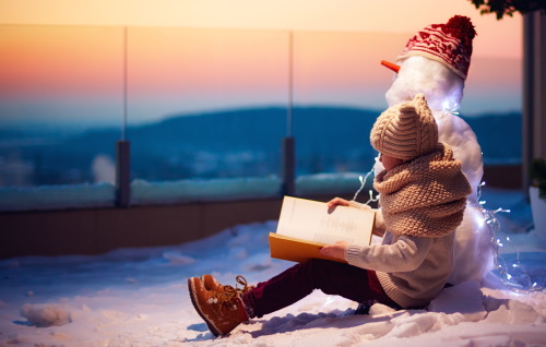 Child reads to snowman