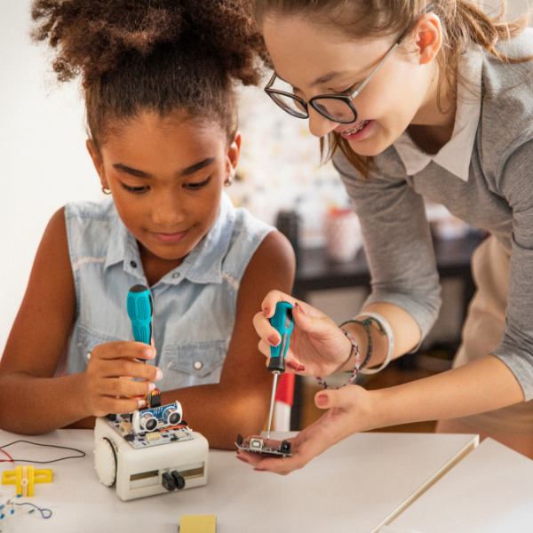 Un enseignante qui aide une enfant à réparer un robot