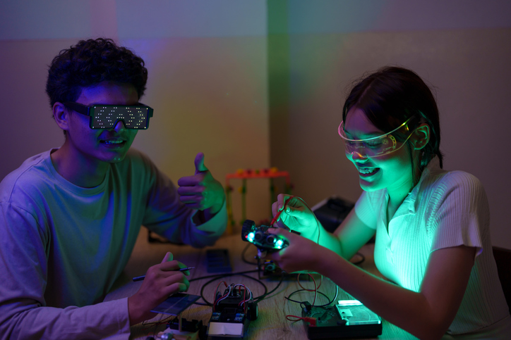 Shown is a colour photograph of a student wearing goggles, and another with an electronic circuit board.