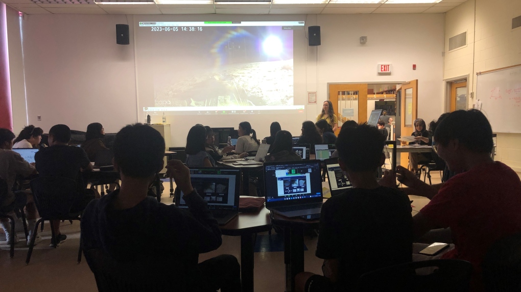 Des élèves dans une salle de classe observent et testent le prototype du rover lunaire.