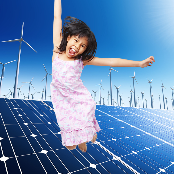 Une enfant qui saute devant des éoliennes et des panneaux solaires