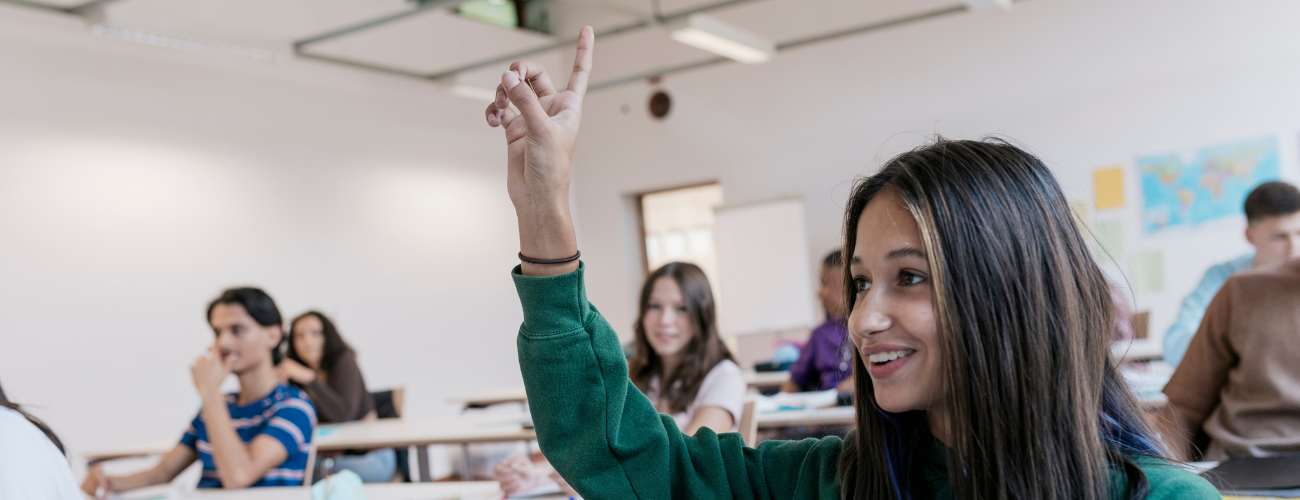 Une adolescente lève la main dans une salle de classe.