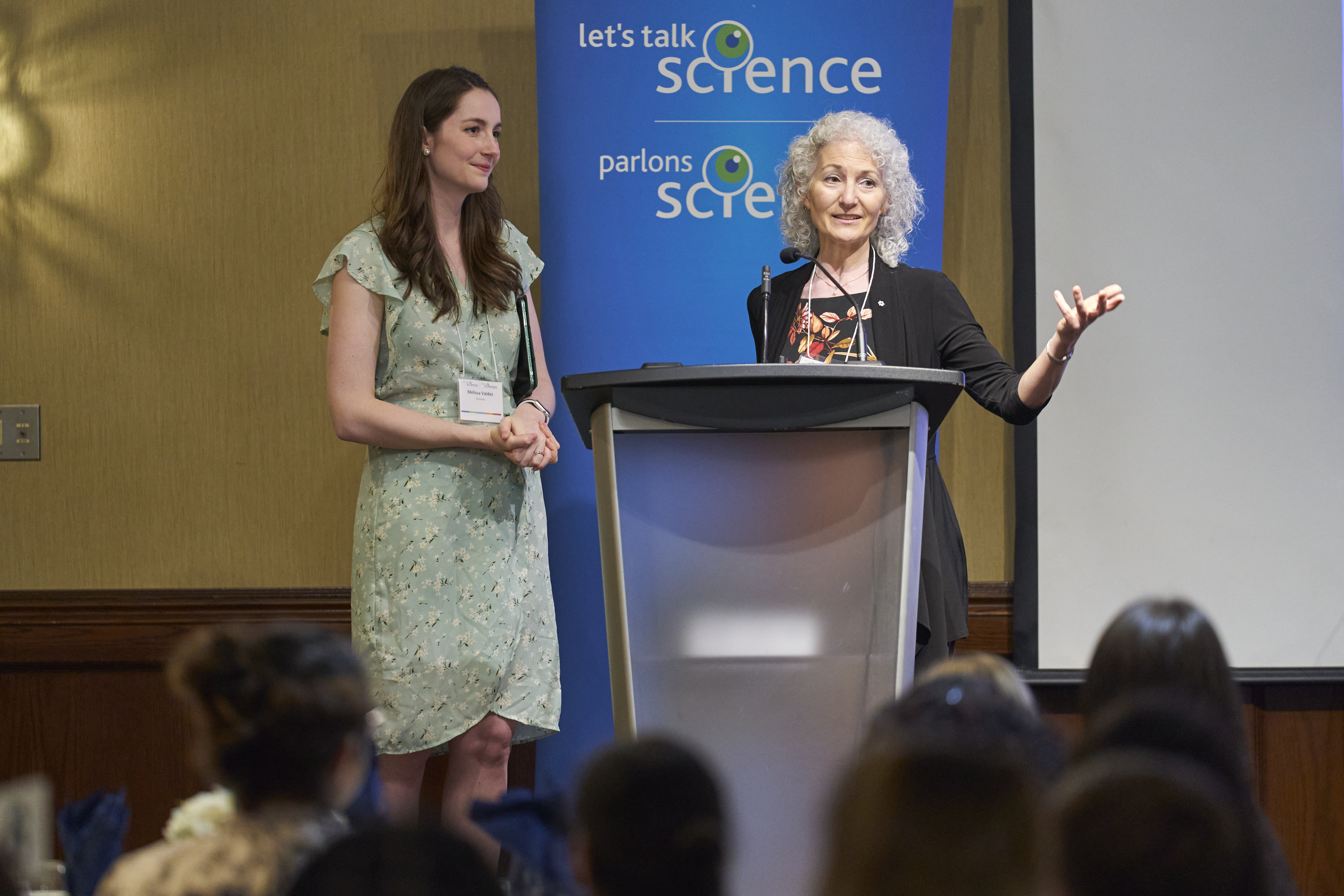 Melissa Valdez and Bonnie Schmidt at a podium in front of a blue Let's Talk Science banner