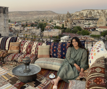 Dure Butt assise sur une terrasse extérieure avec une ville turque en arrière-plan. 	