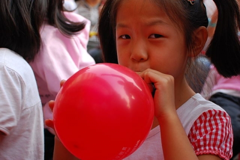 Une petite fille qui gonfle un ballon