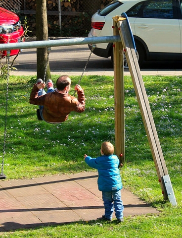 Petit garçon poussant un adulte sur une balançoir