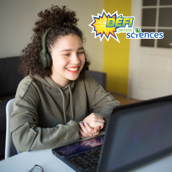 Une étudiante qui regarde son ordinateur en souriant. 