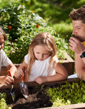 Enfants avec de petites pelles creusant dans le jardin avec un adulte