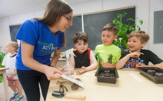 Une bénévole de Parlons sciences travaille sur le projet Tomatosphère avec trois élèves.