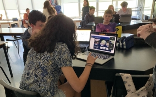 Des élèves dans une salle de classe observent et testent le prototype du rover lunaire.