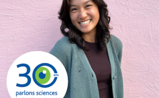 Caroline Huang souriante devant un mur rose portant le logo du 30e anniversaire de Parlons sciences