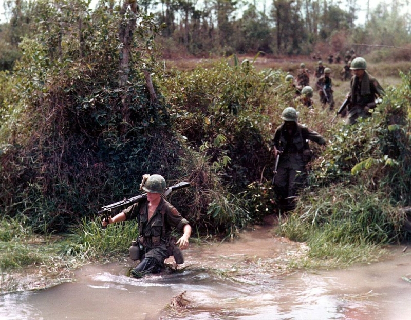 Soldats américains pataugeant dans un ruisseau inondé durant la Guerre du Vietnam en 1968