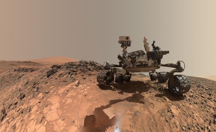 Cette photo montre le rover Curiosity et la surface rocheuse aride de Mars.