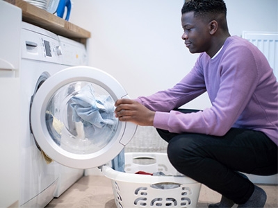 Young man loading a washing machine