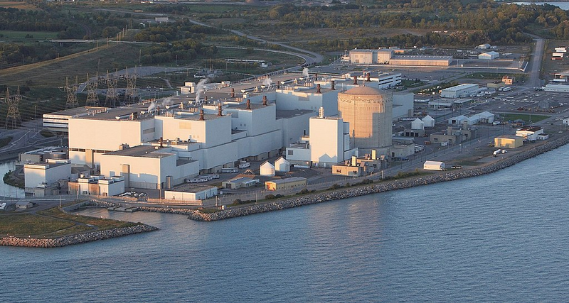 Shown is a colour photograph of the buildings that make up the Darlington nuclear power facility on the shore of Lake Ontario.