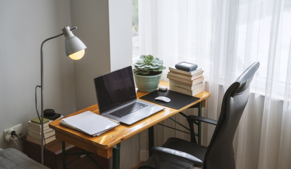 a home office setup with lamp, computer, plant, books, mouse, and chair.
