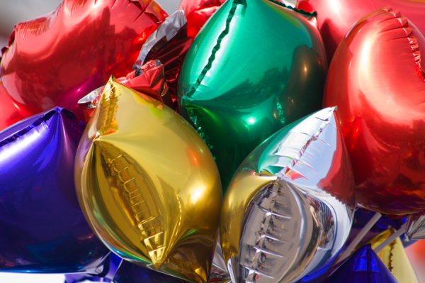 Shown is a colour photograph of brightly-coloured balloons packed closely together.