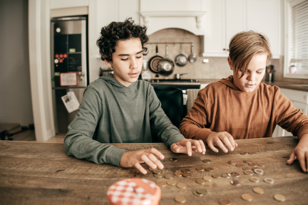 Shown is a colour photograph of two people counting coins at a kitchen table.