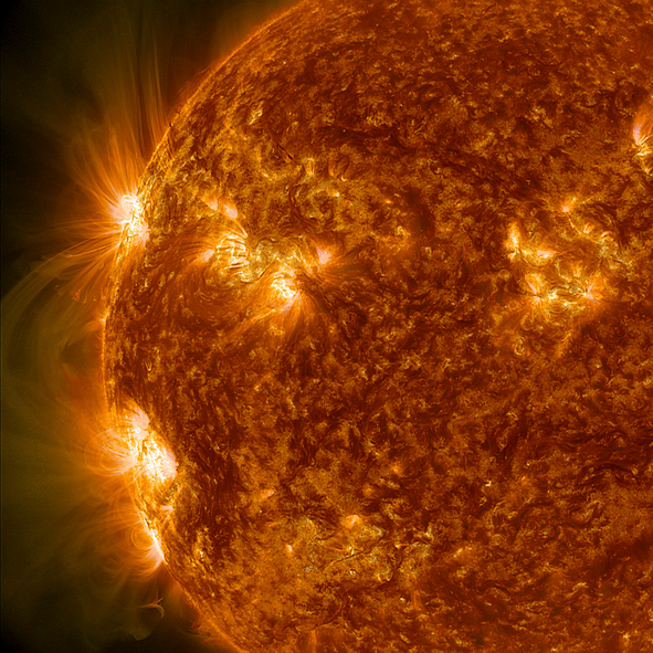 Shown is a colour illustration of loops of yellow light bursting up from the surface of the Sun.