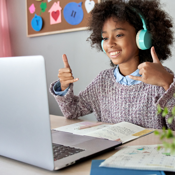 Une fille portant des écouteurs qui sourit devant son ordinateur